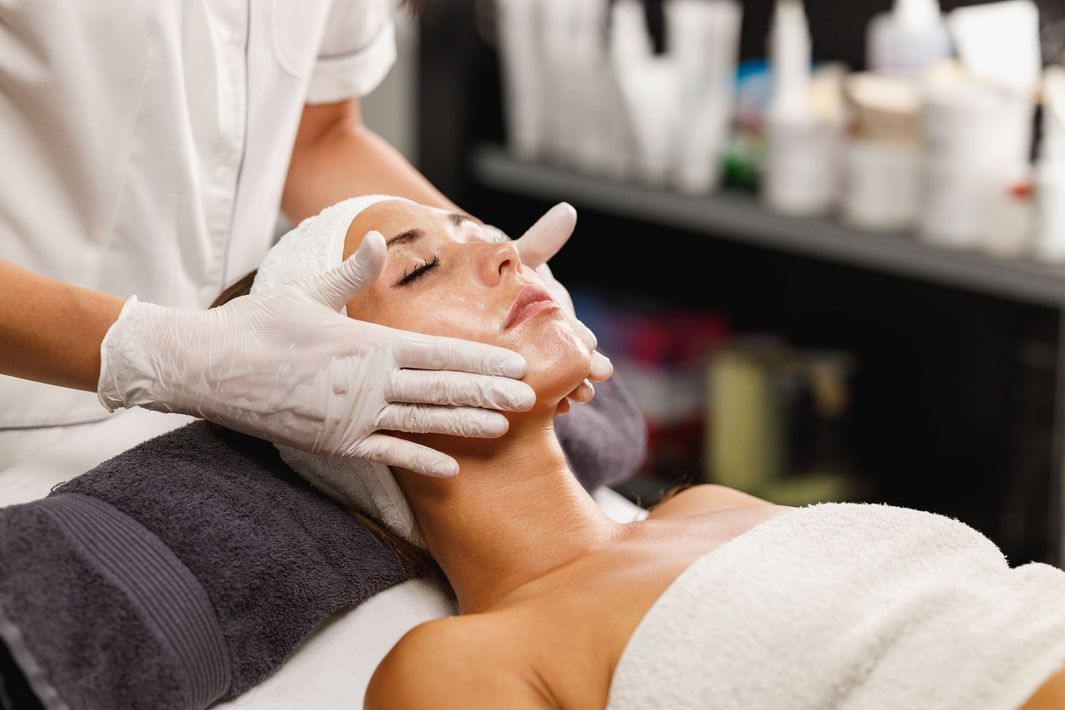 Spa facial treatment with gloved hands applying cream to a reclining client