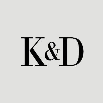 Black serif letters “K&D” on a light gray background