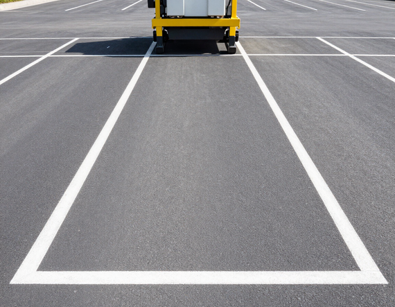 Empty parking lot with white painted lines and a yellow vehicle at the top edge
