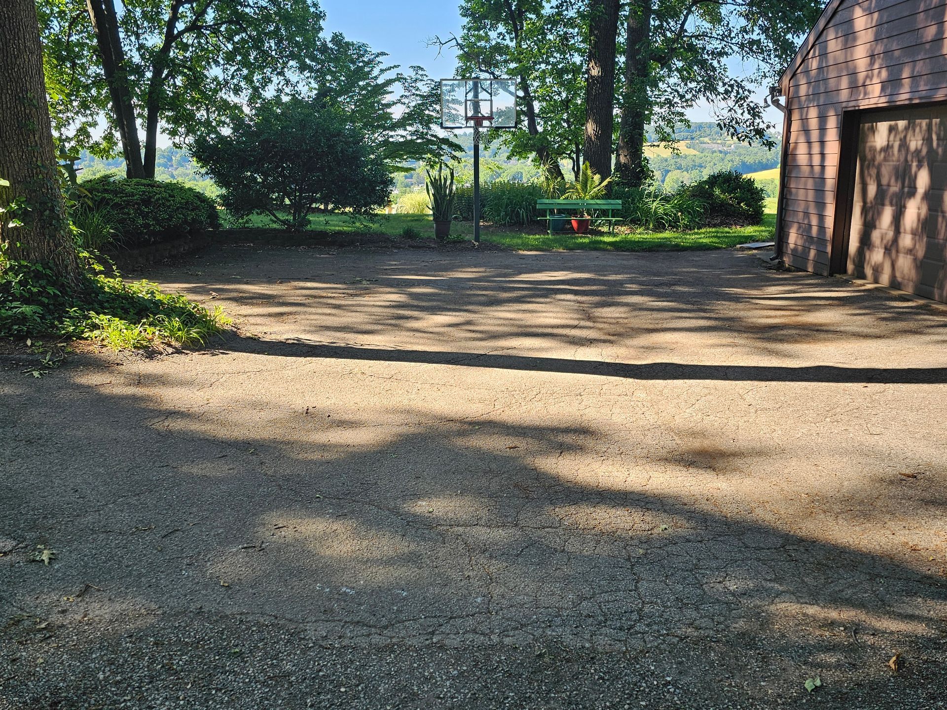 Shaded gravel courtyard with trees, a picnic table in the distance, and a barn on the right