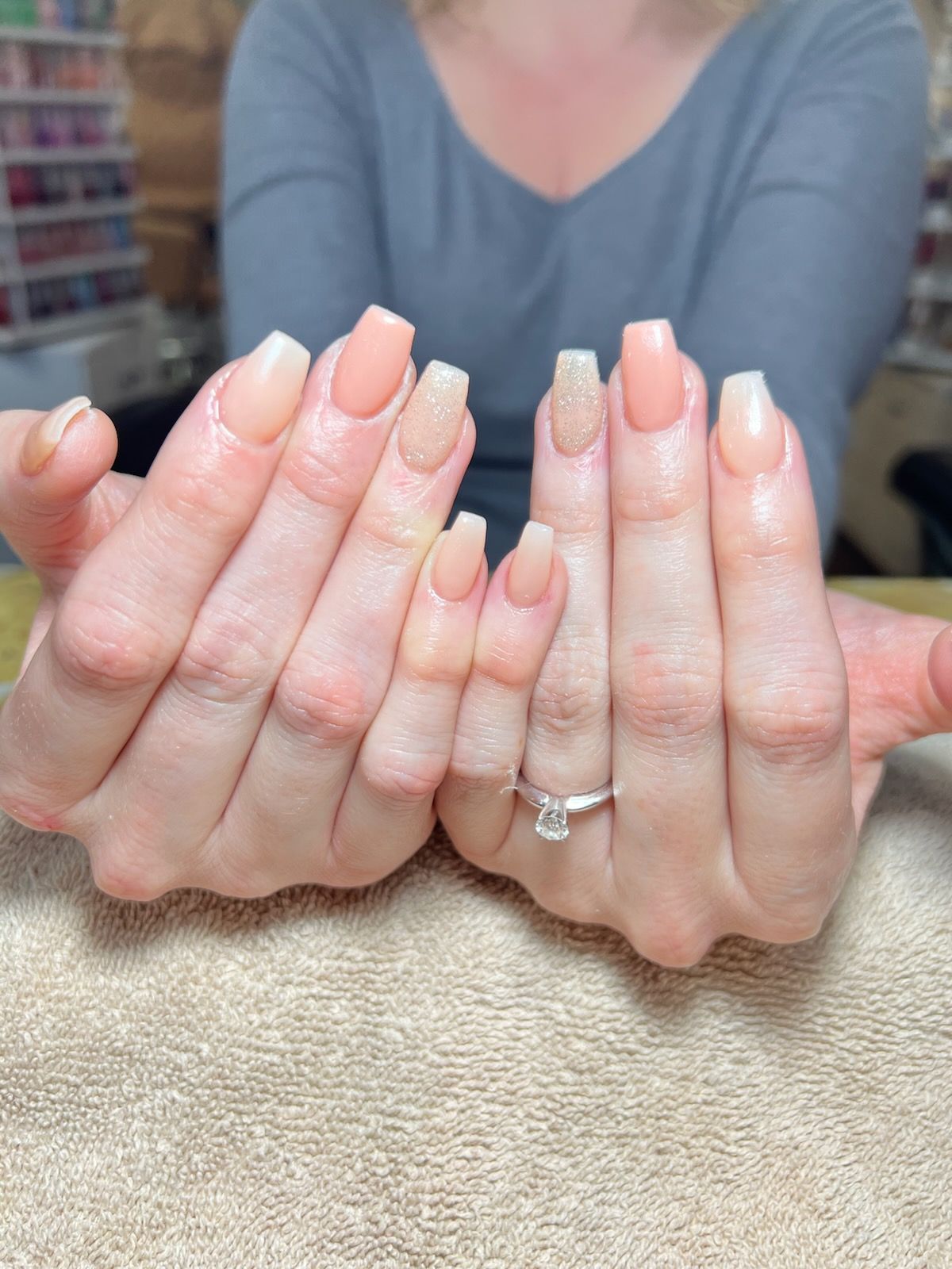 Close-up of manicured hands with coffin-shaped nails painted in alternating shades of nude and glittery gold.