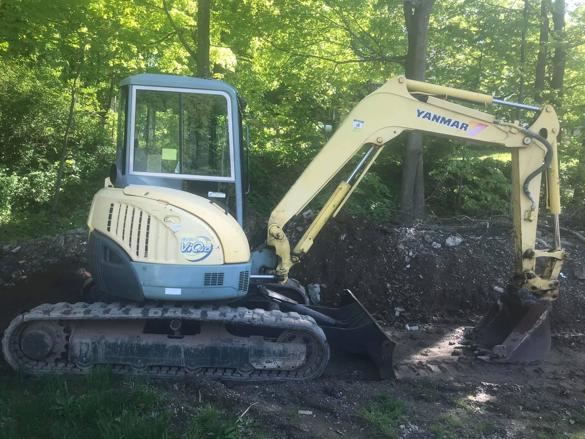 A yanman excavator is sitting on top of a pile of dirt.
