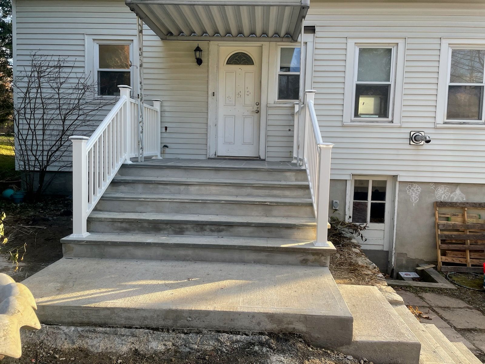 A white house with concrete steps and a white railing