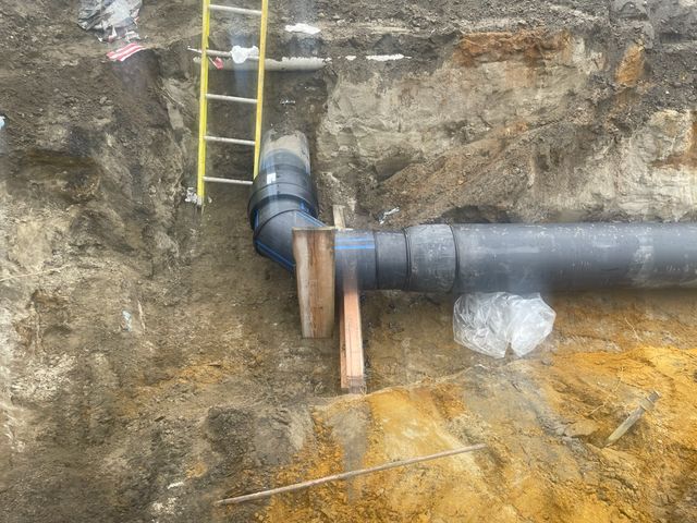 A large pipe is sitting in the dirt next to a ladder.