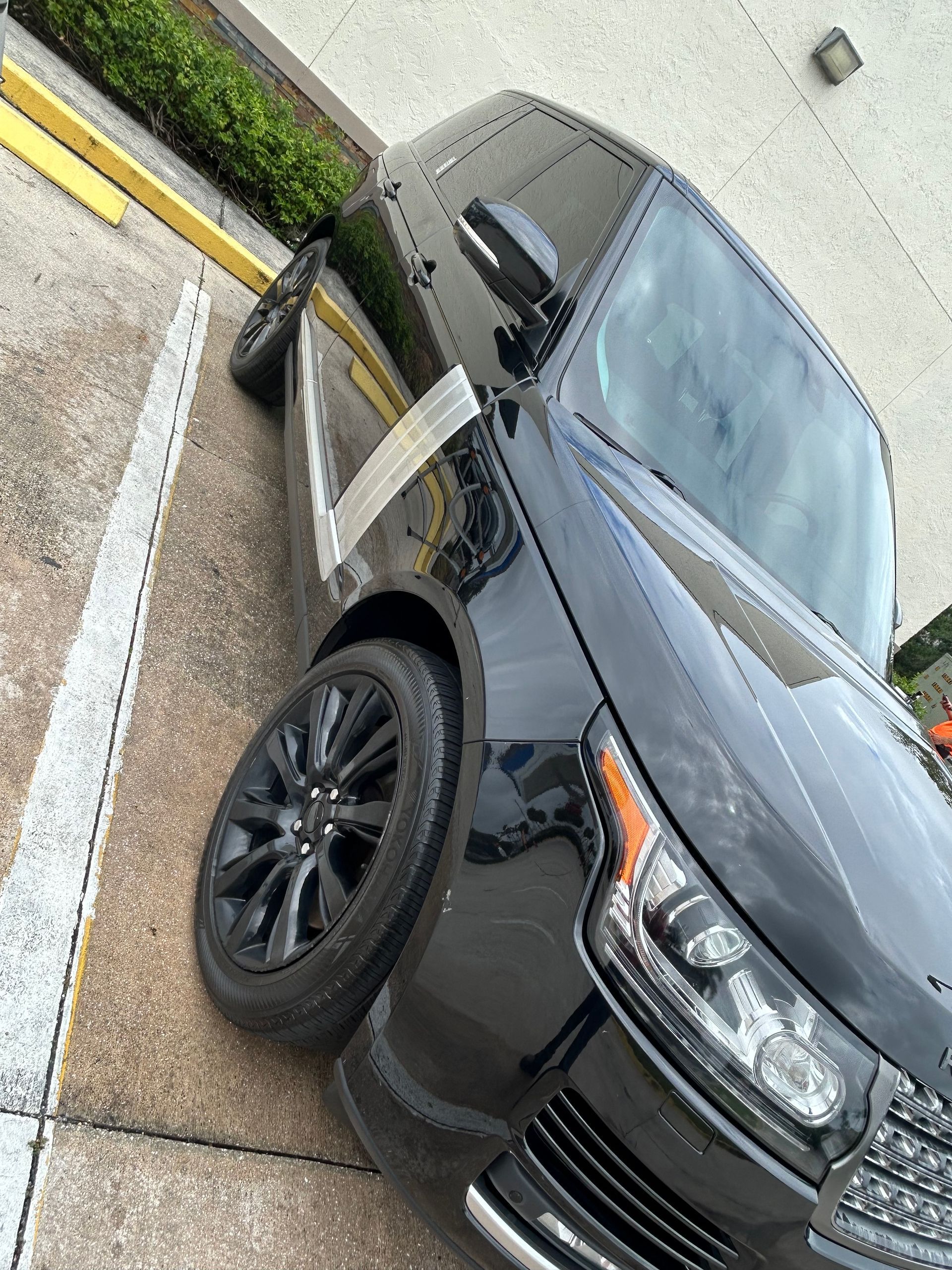 Black Range Rover SUV parked diagonally on a concrete surface with black wheels.