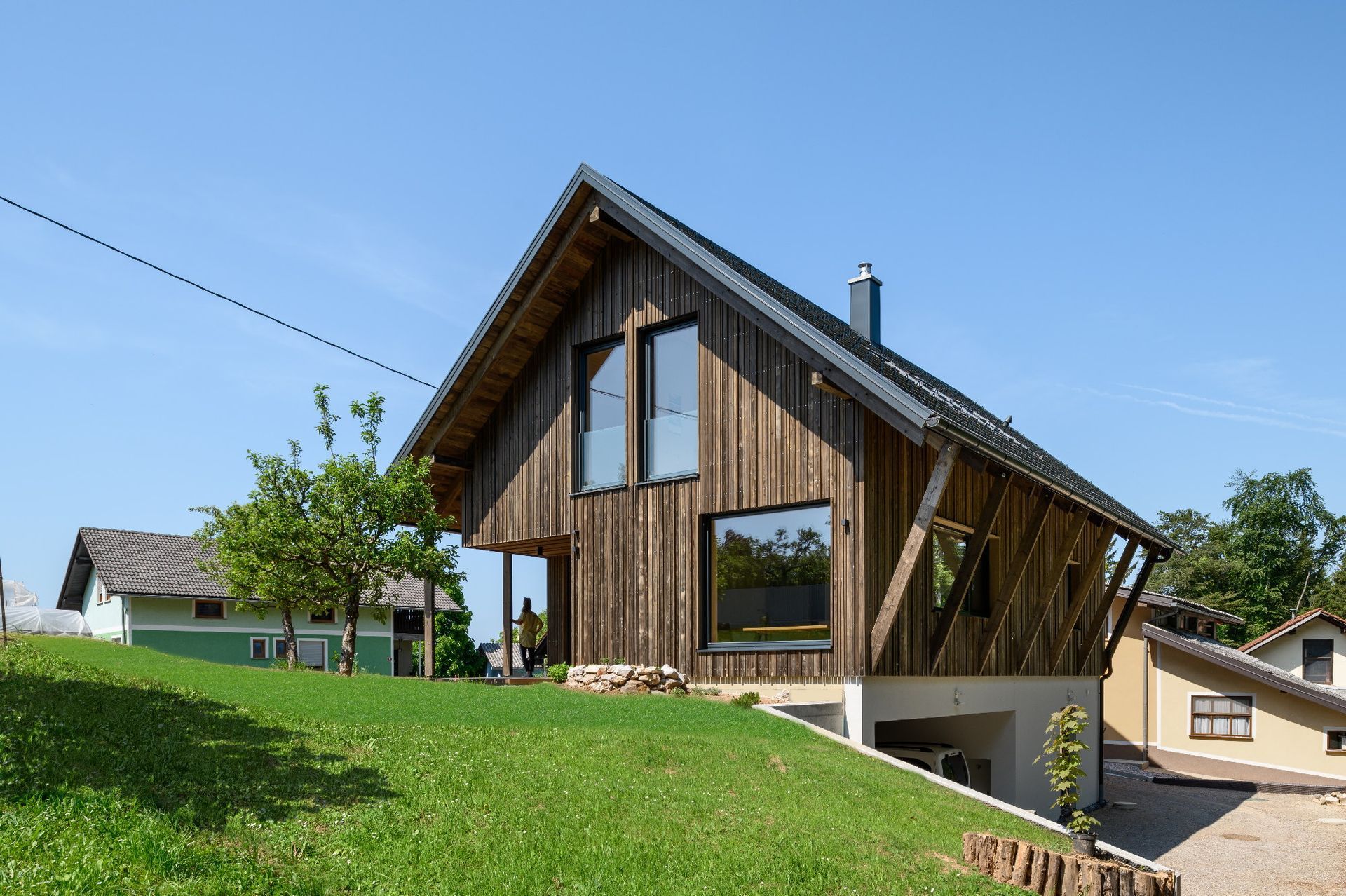 Casa moderna in legno con grandi finestre su una collina erbosa sotto un cielo azzurro