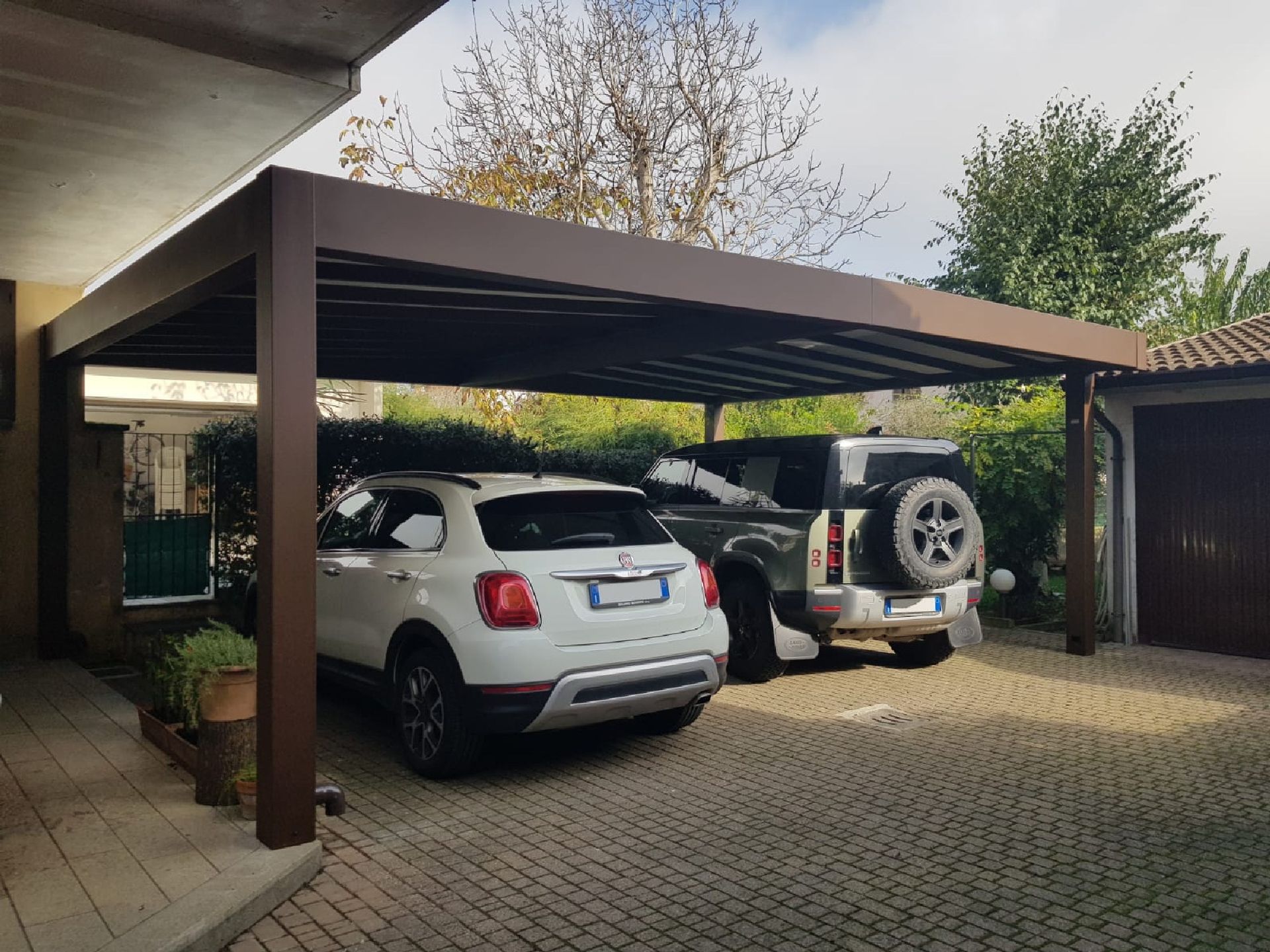 Vialetto coperto con due SUV parcheggiati accanto a una casa