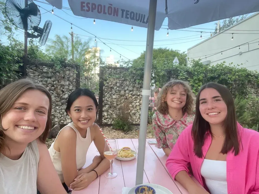 A group of women are sitting at a table under an umbrella.