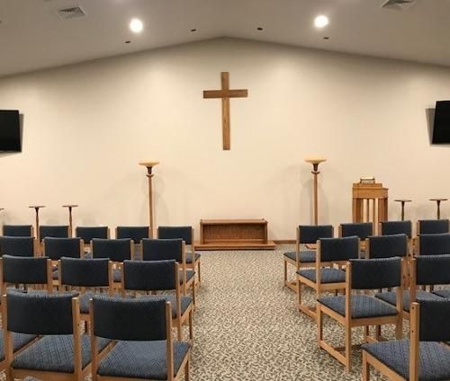 Interior of a church sanctuary with chairs, a cross, and an altar.