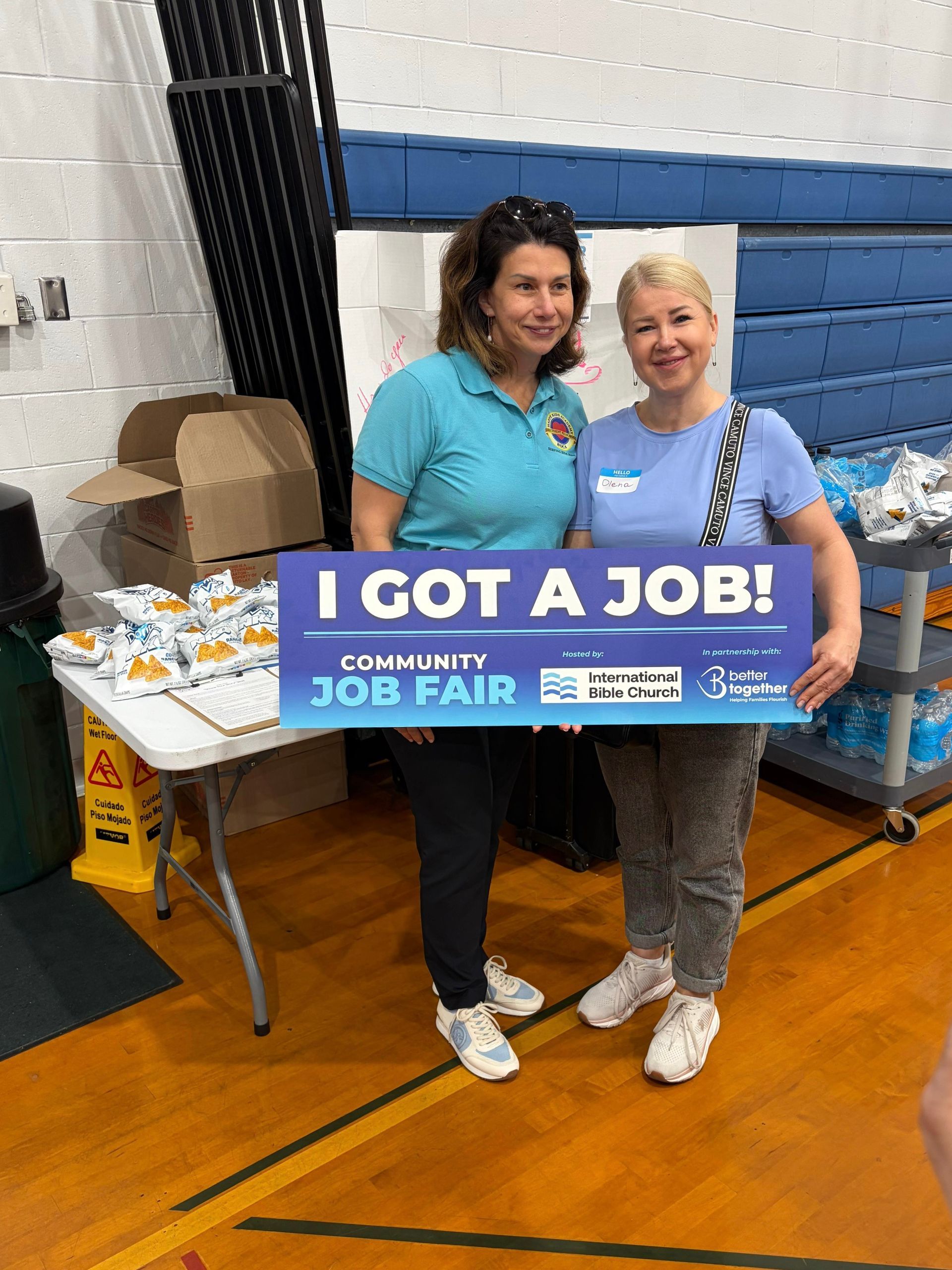 Two people smiling and holding “I Got a Job!” sign at a community job fair