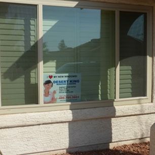 Window with a “Desert King” flyer taped inside, seen from outside a house.