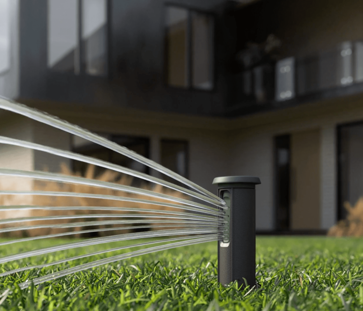 A sprinkler is spraying water on a lush green lawn in front of a house.