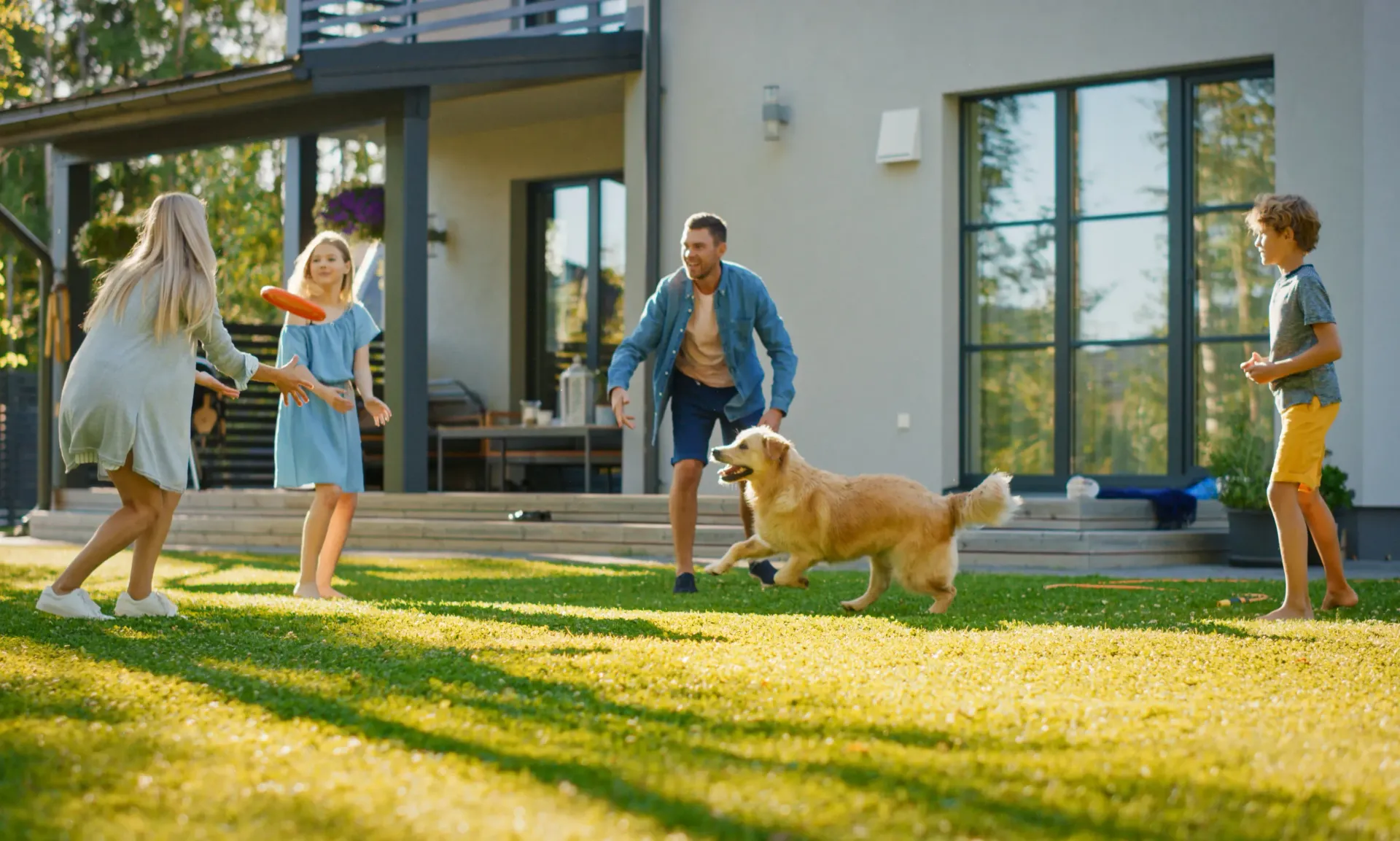 A family is playing frisbee with their dog on their new sod lawn.