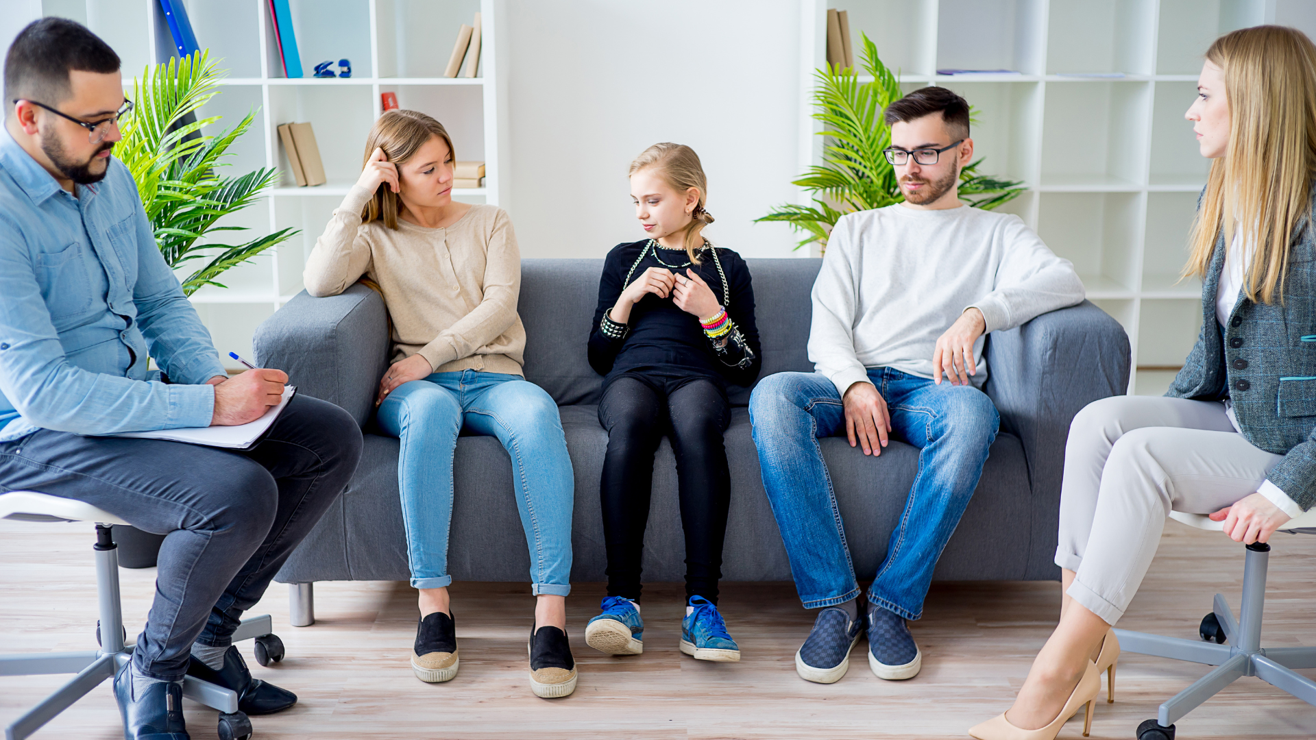 A family is sitting on a couch and talking with a counselor.