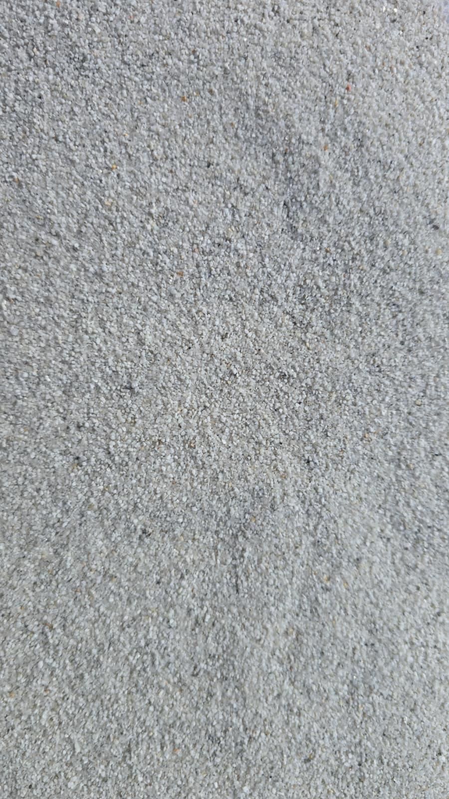 Primo piano di una superficie di cemento grigio ruvido con una texture punteggiata.