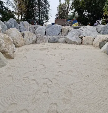 Fossa di pietra riempita di sabbia, circondata da grandi rocce e alberi all'aperto