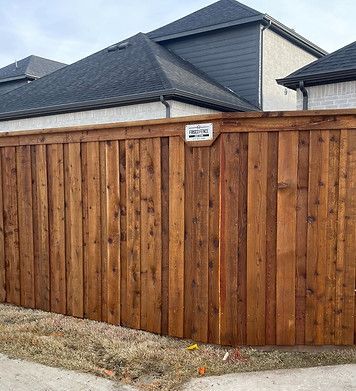 A wooden fence is in front of a house.