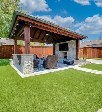 There is a pavilion with a fireplace and a television in the backyard.