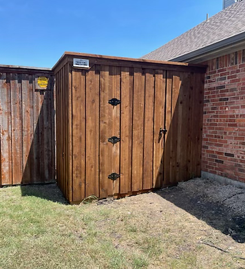 A wooden shed is sitting next to a brick house.