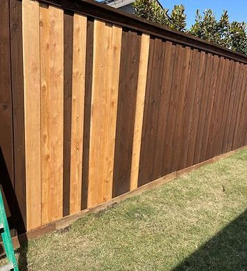 A wooden fence is sitting on top of a lush green lawn next to a ladder.