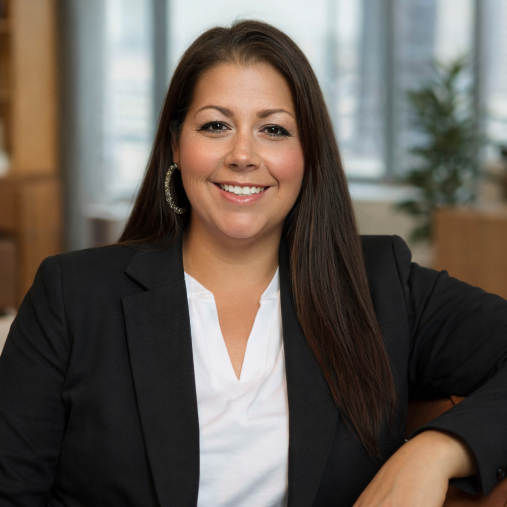 Smiling woman in a black blazer and white blouse in an office setting