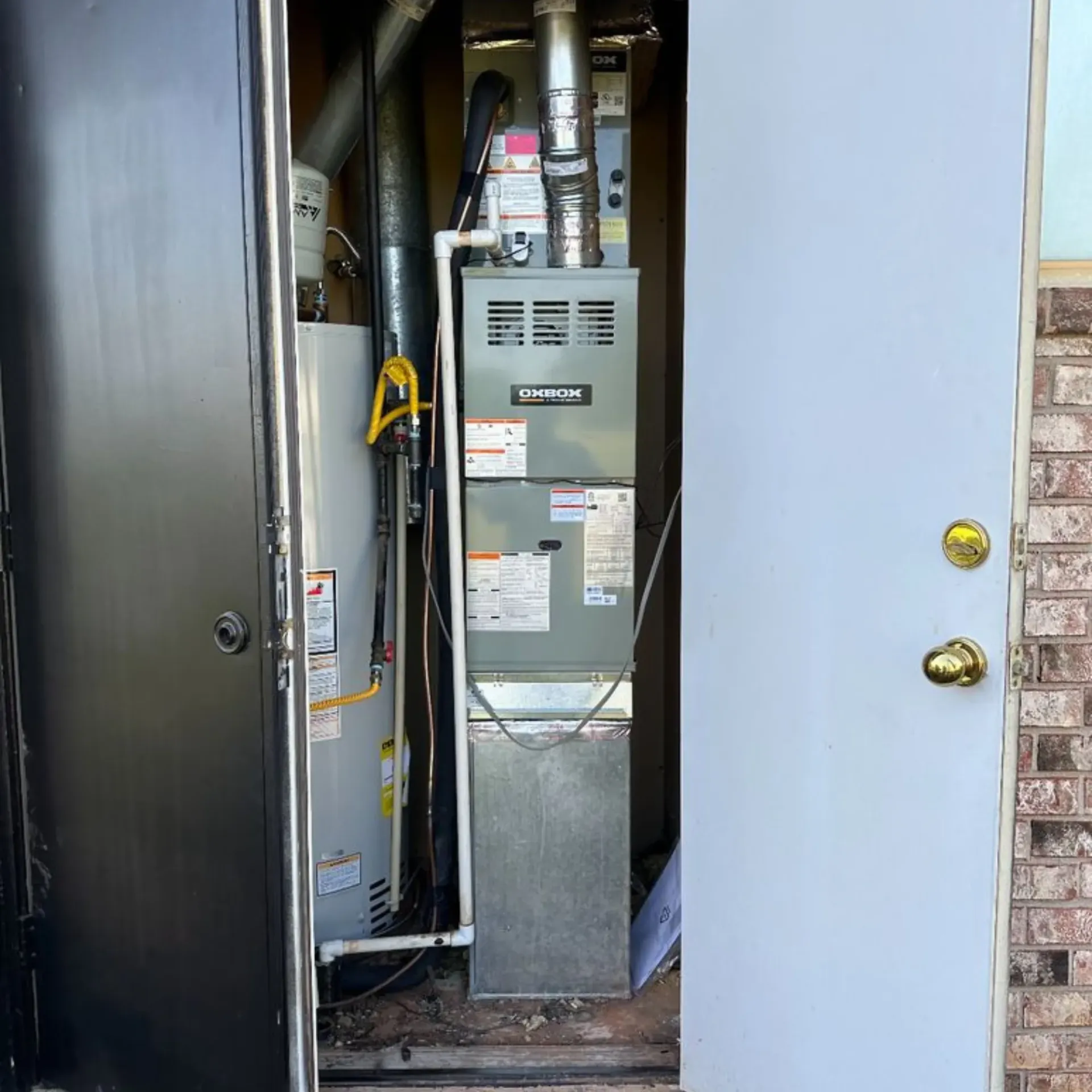 Finnegan’s Heating Air Conditioning - An air conditioner is sitting inside of a doorway next to a water heater.