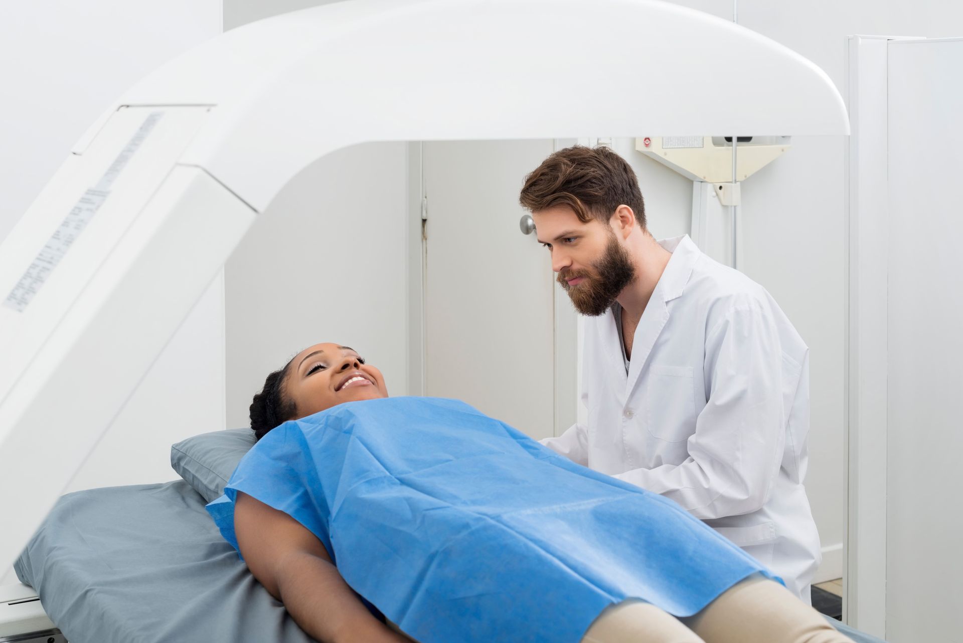 Paciente realizando um exame de densitometria óssea com um técnico em ambiente médico.