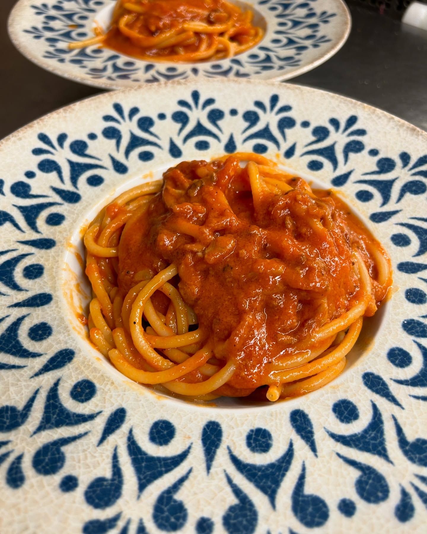 Due piatti di spaghetti al sugo di pomodoro su piatti decorati con motivi blu e bianchi.
