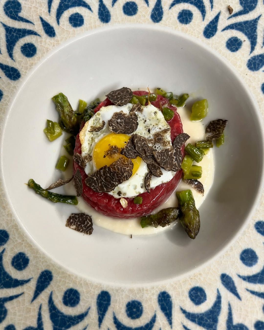Insalata di barbabietole con formaggio di capra, erbe aromatiche e olive servita su un piatto blu decorato.
