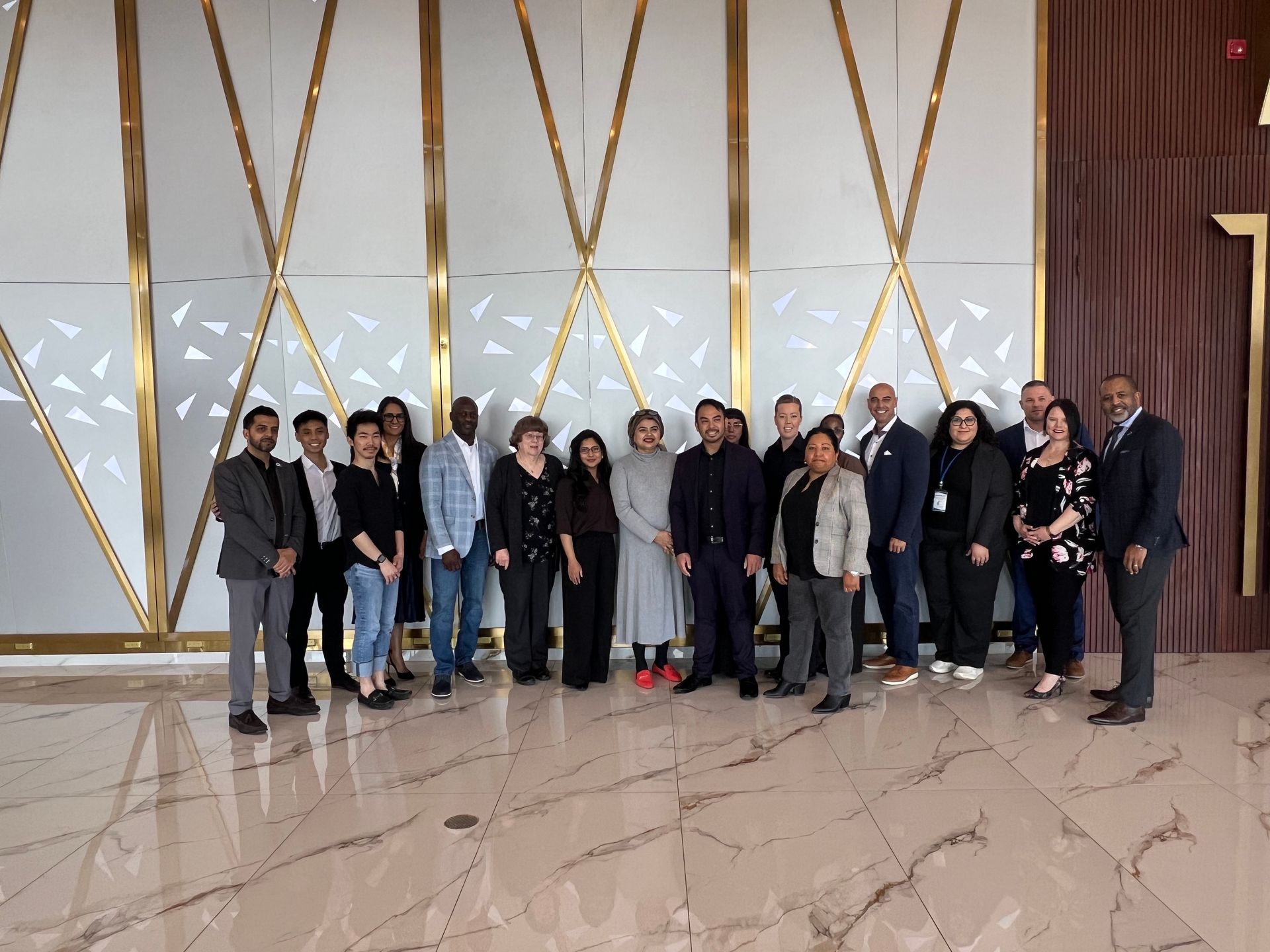 Group of people posing in a modern lobby with gold wall accents and polished marble floor