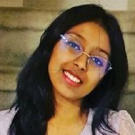A close up of a woman wearing glasses and smiling.