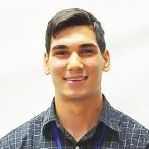 A young man in a plaid shirt is smiling for the camera.