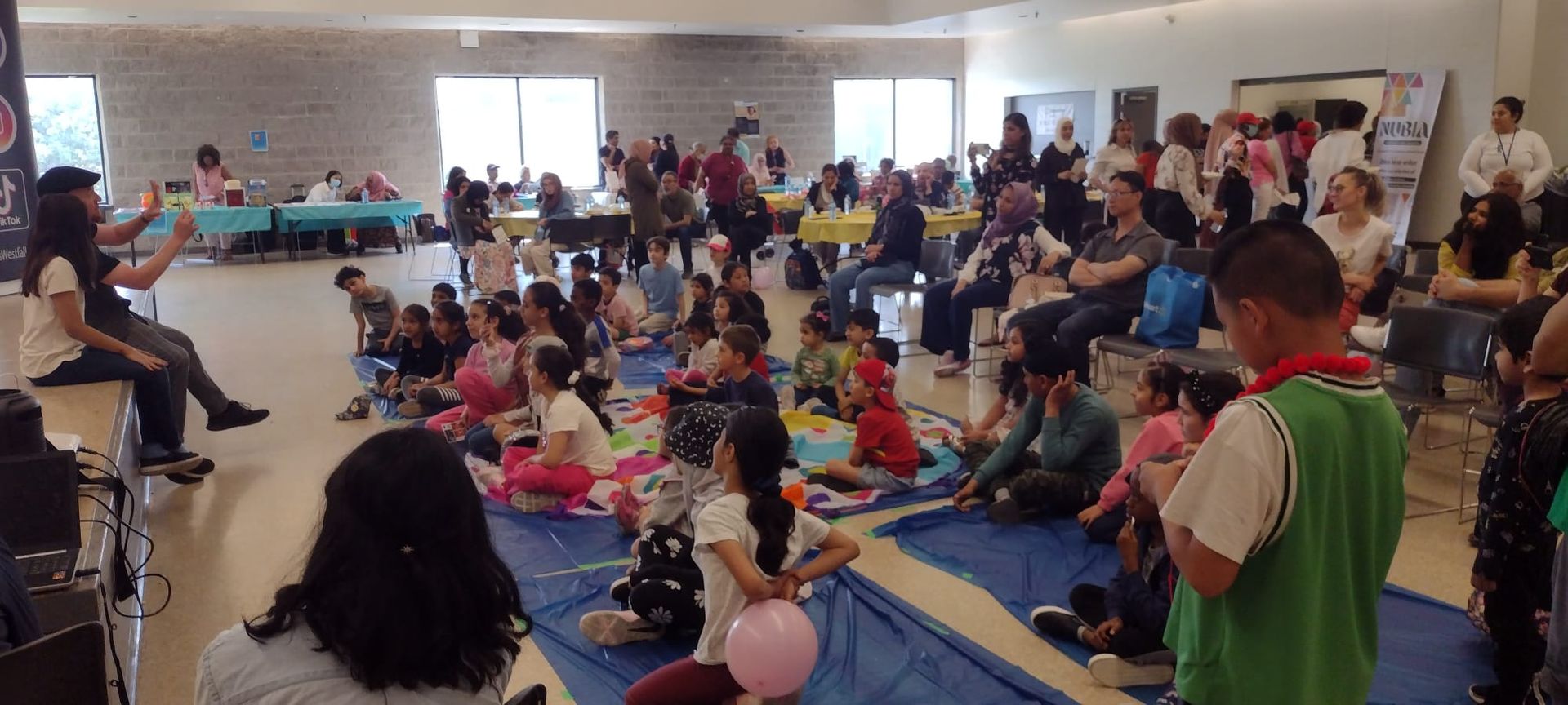 A large group of people are sitting on the floor in a room.