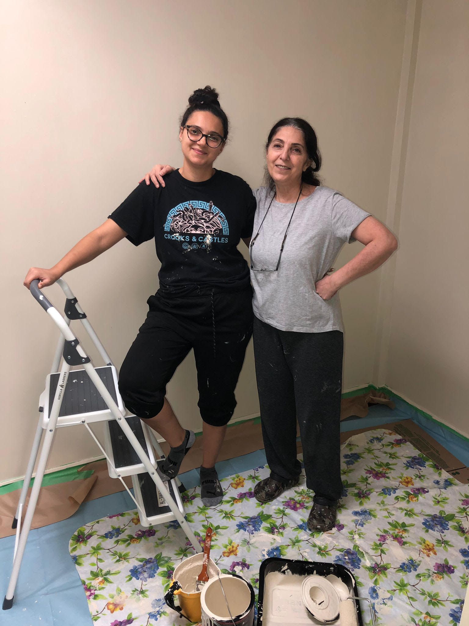 Two women are standing next to each other in a room with a ladder.
