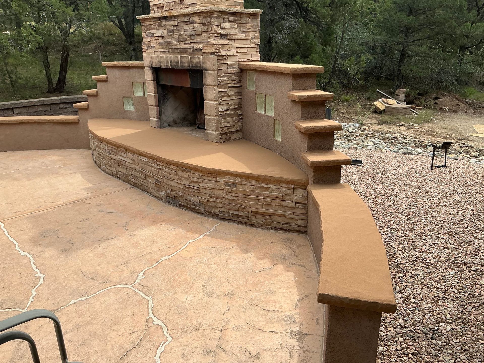 Modern patio with outdoor seating, grill, string lights, and stone flooring beside a white house