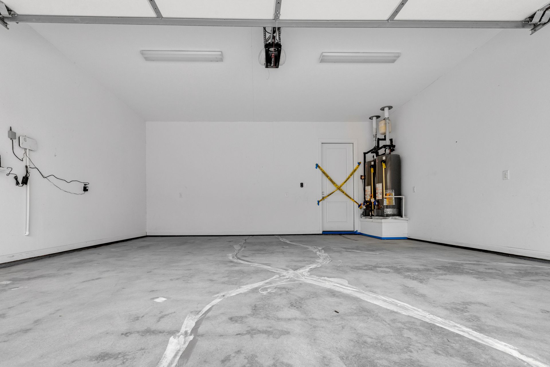 Empty white garage with gray concrete floor and a wall-mounted mechanical unit near the right wall