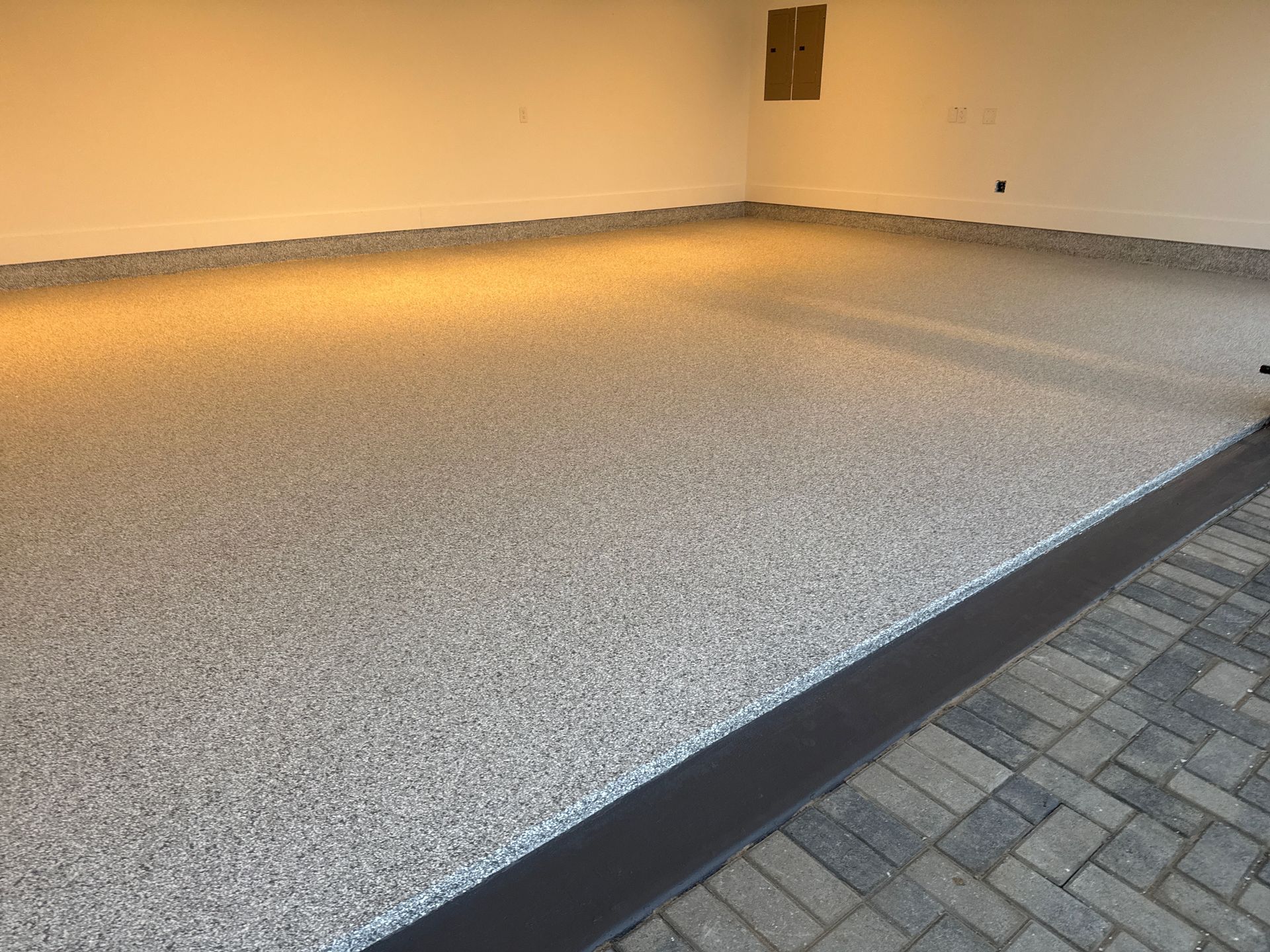 Empty indoor patio with a speckled floor, dark border trim, and beige walls.