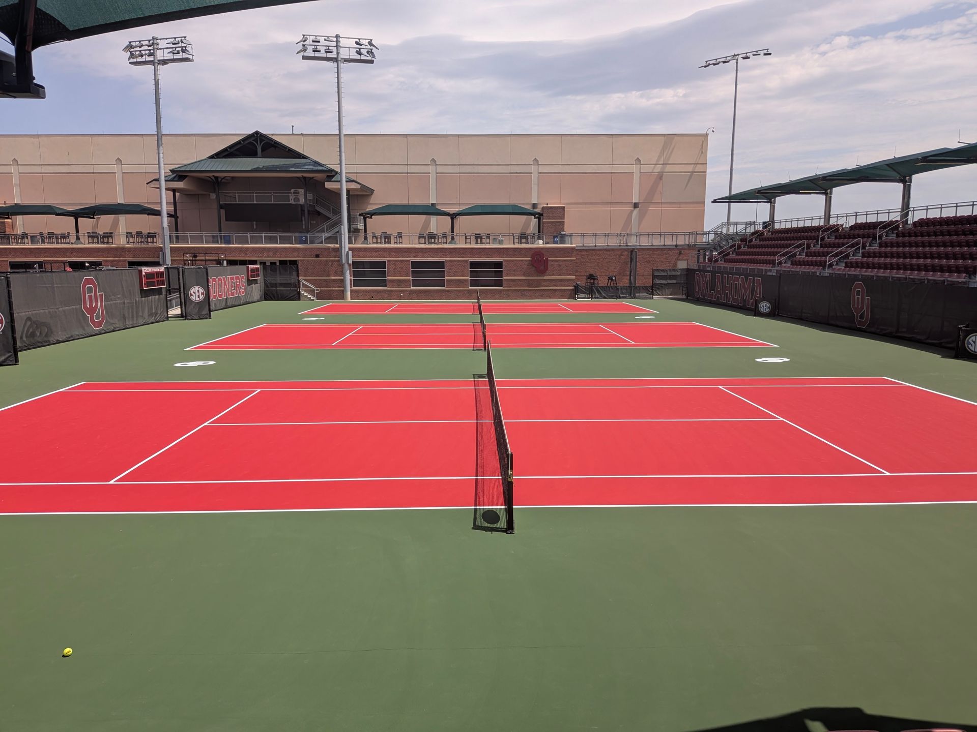 Yellow perforated ball on a blue court with a blurred net in the background
