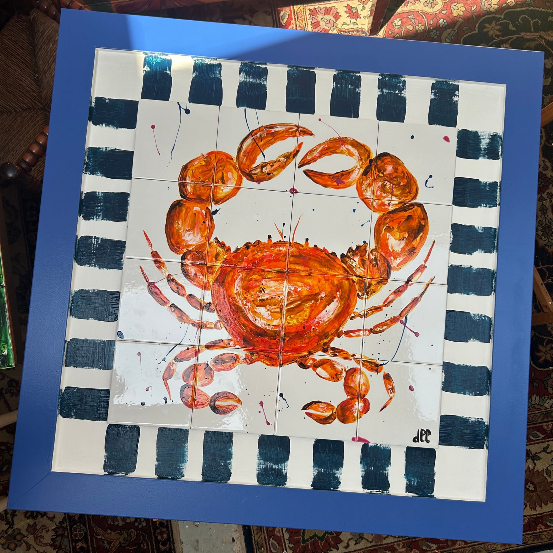 Oranje rode krab met alle kleuren spetters op blauw wit gestreepte lijst met kobalt blauweand. Tegeltableau 16 tegels á 15 x 15 cm. Totale omvang 90 x 90 cm. handbeschilderde tegeltjes afgebakken in oven keukendecoratie wanddecoratie keukendesign interieur kleurrijkwonen. tegeltableaus, tegelkunst, tegeltjekunst, wandtegels, handbeschilderde tegels.