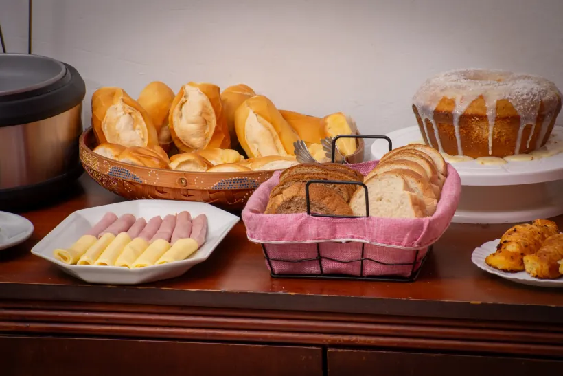 Uma mesa coberta com pratos de comida e bebidas. pousada-ocacocar