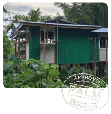 PALM worker Pattson standing with a woman in front of a newly built green house, representing his achievements through the program.