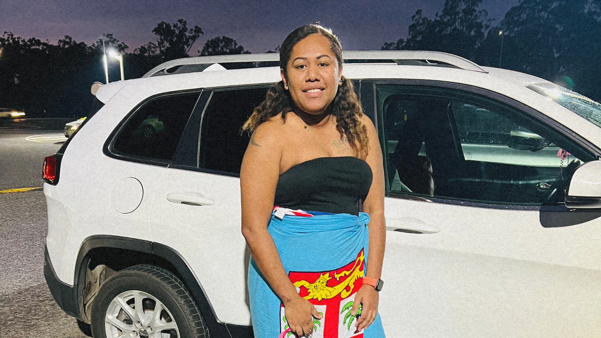 Elenoa, a PALM scheme worker, standing in front of her car, celebrating her journey and achievements.