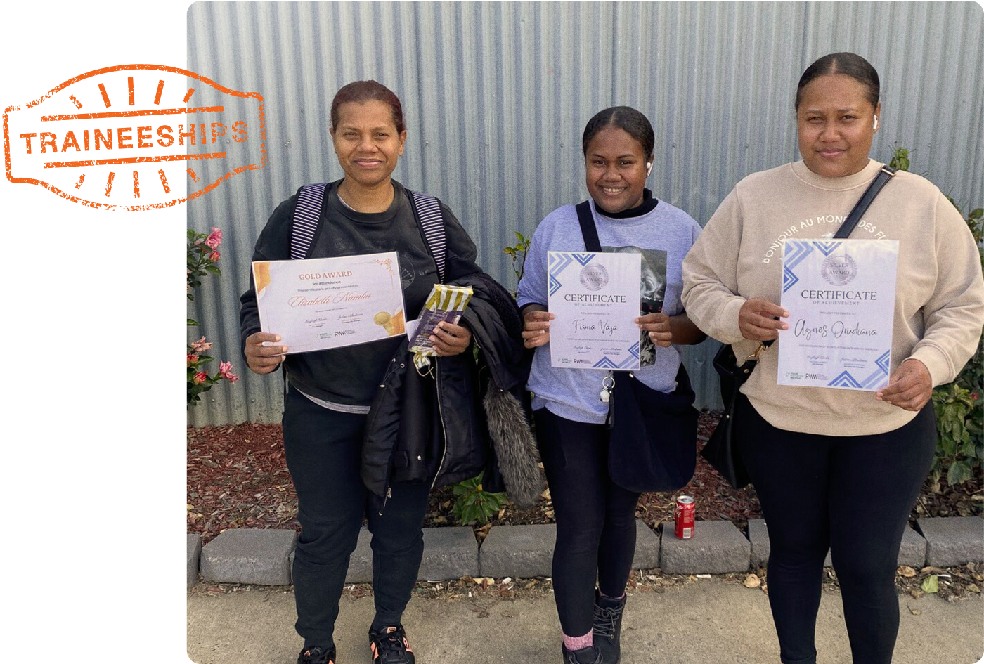 Three women are standing next to each other holding papers.