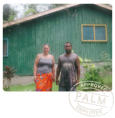 PALM worker Pattson standing with a woman in front of a newly built green house, representing his achievements through the program.