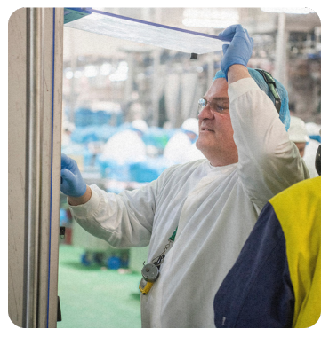 A man wearing blue gloves is working in a factory