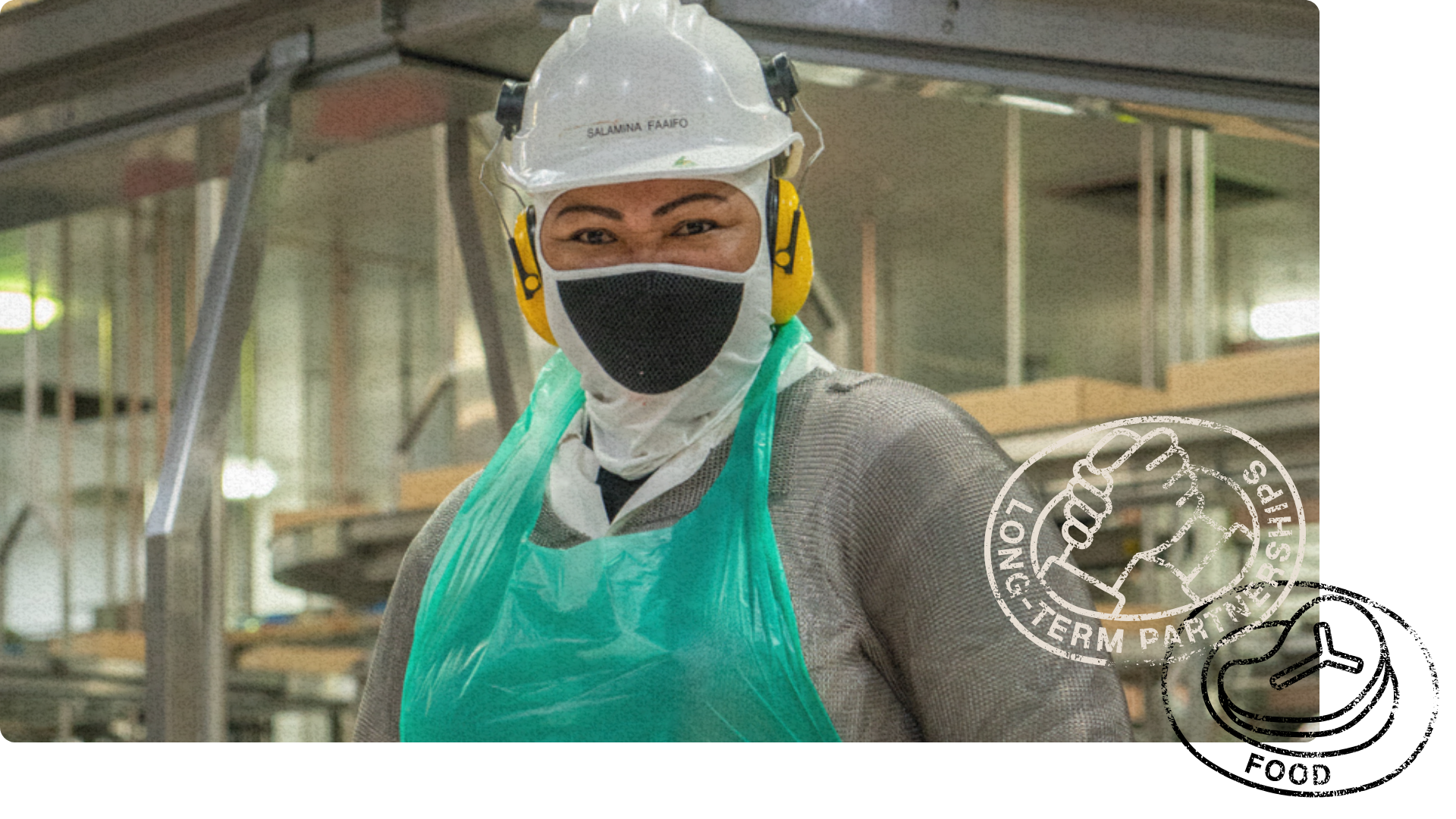 Smiling worker in protective gear, including a hard hat, face mask and apron, standing in an industrial setting. 'Long-Term Partnerships' stamp in the corner.