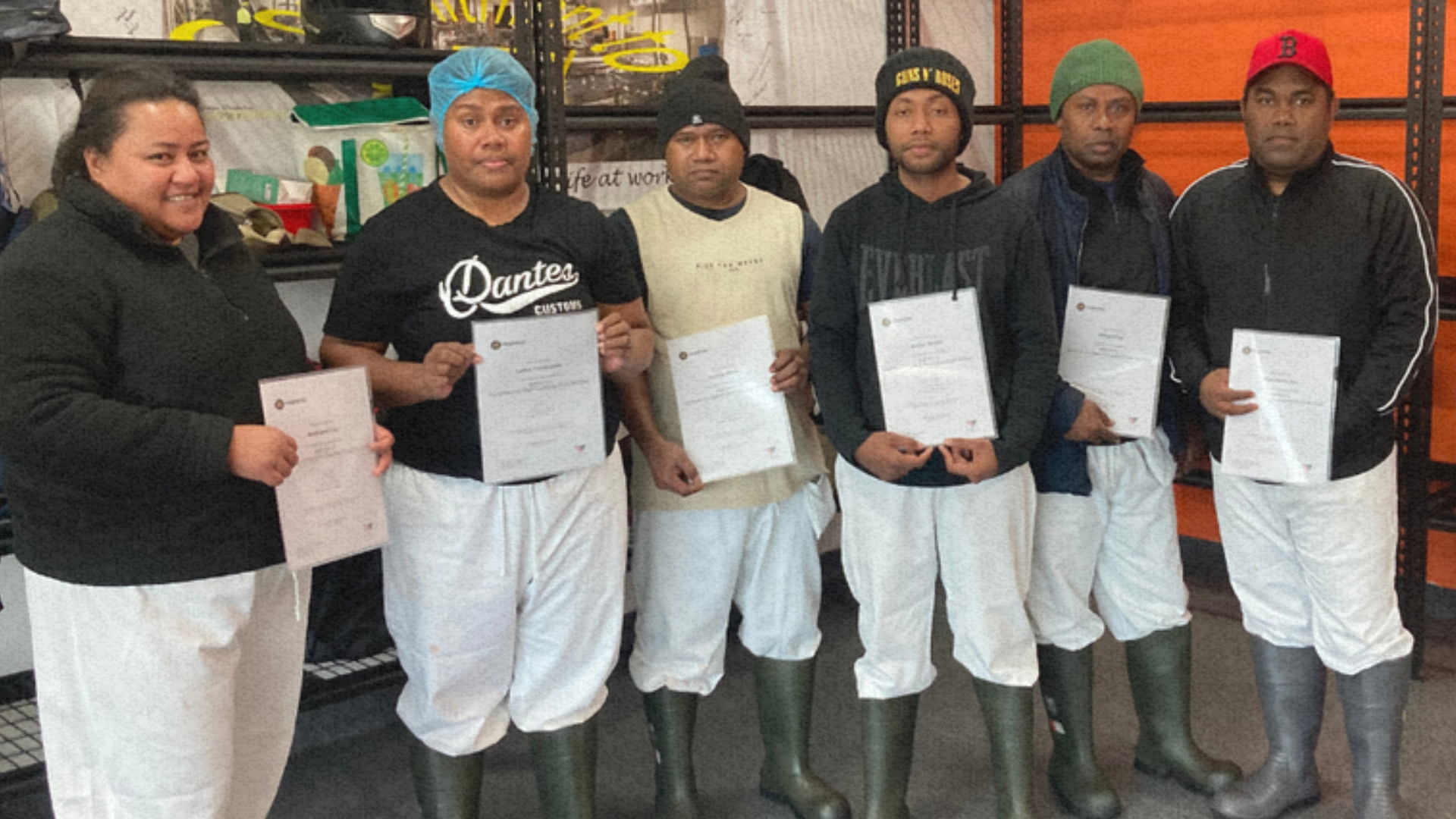 Six PALM scheme workers standing together in work attire, holding certificates and smiling, representing their achievement in the beef industry.