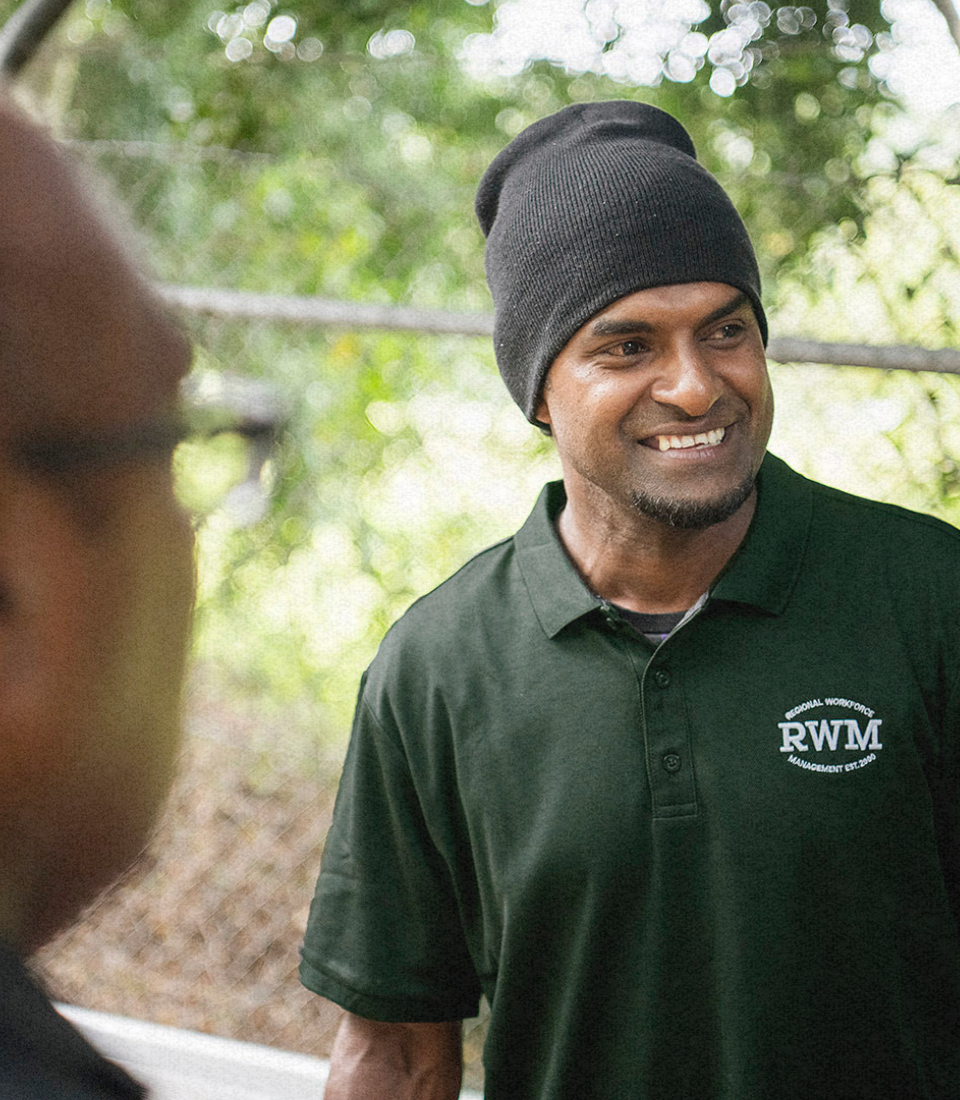 A man wearing red gloves is smiling in a field