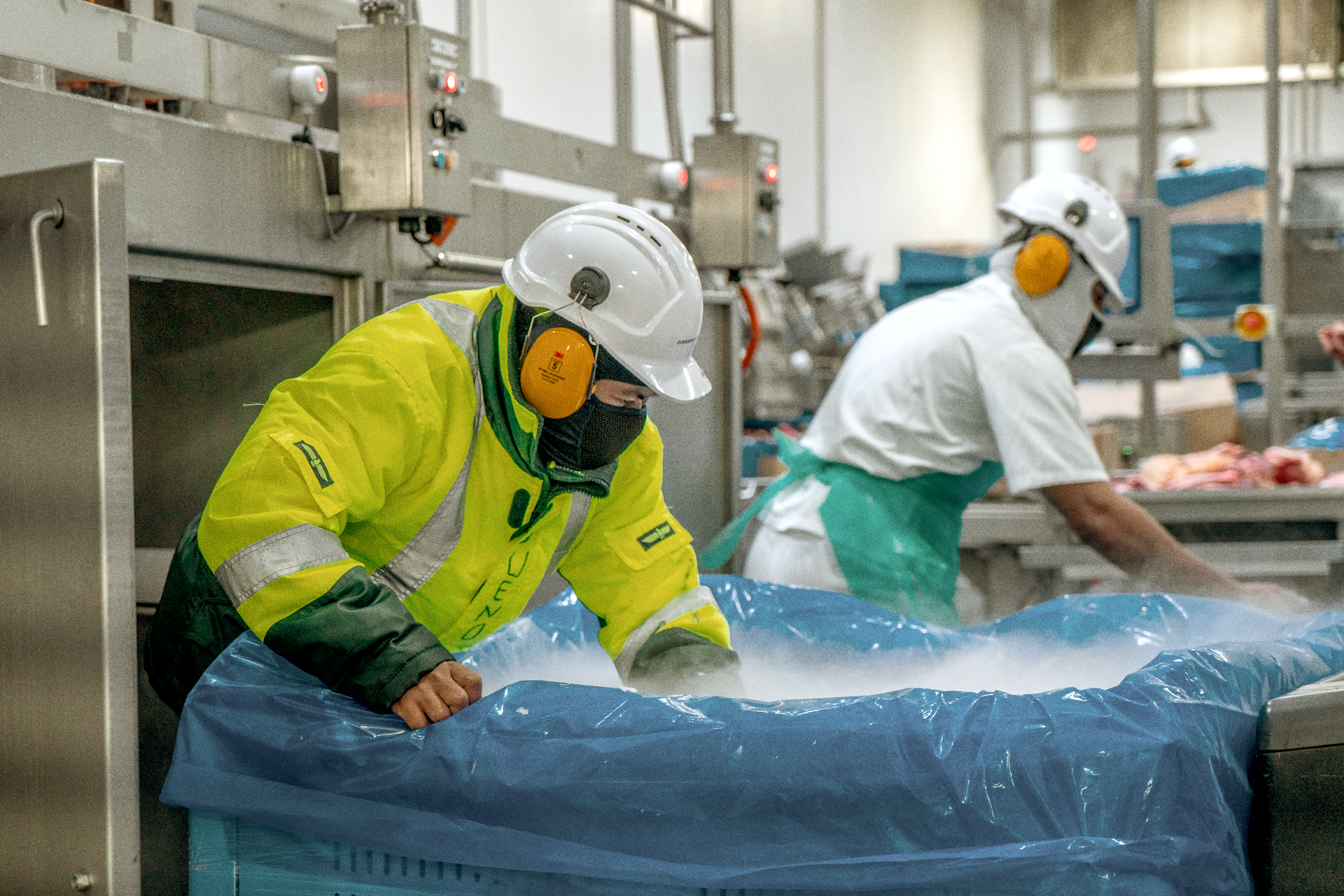 A man in a yellow jacket is working in a factory.