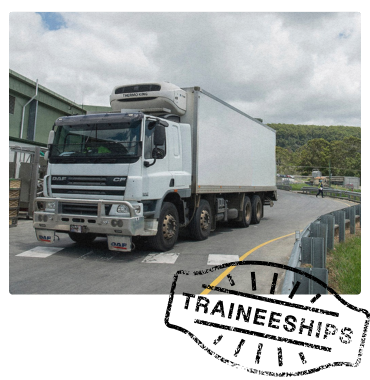 A refrigerated truck parked at a logistics facility, with crates nearby and a winding road leading into a hilly, rural area.